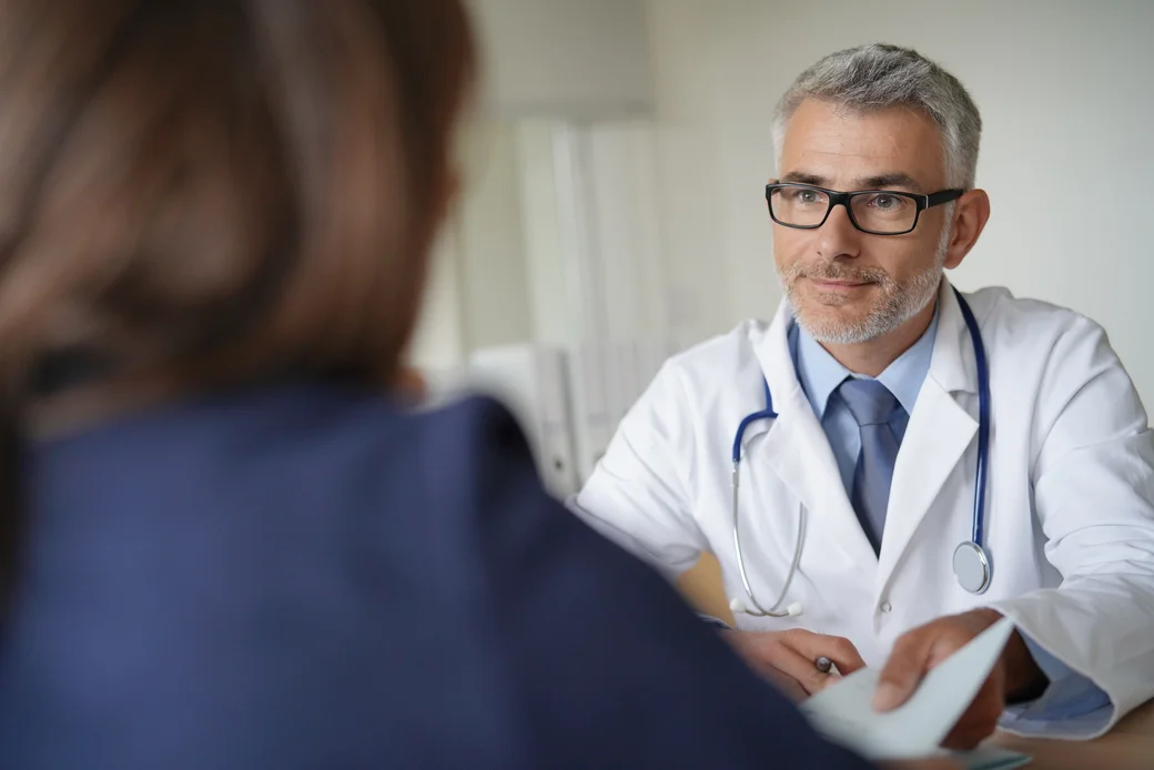 Betriebsarzt sitzt beschäftigter Person gegenüber