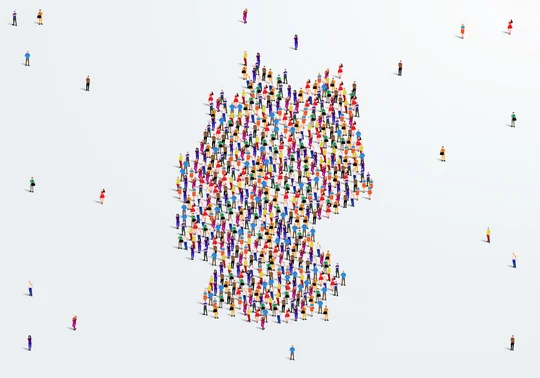 Große Gruppe von Menschen bilden sich, um eine Form der Deutschlandkarte zu erstellen.